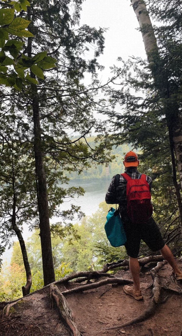 Hiker standing on a wooded overlook above a misty lake